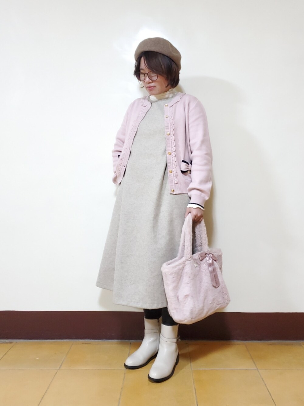 ピンク系のニット/セーター、ベージュ系のジャンパースカート、ホワイト系のTシャツ/カットソーを着用したレディースの冬コーディネートの2枚目の写真