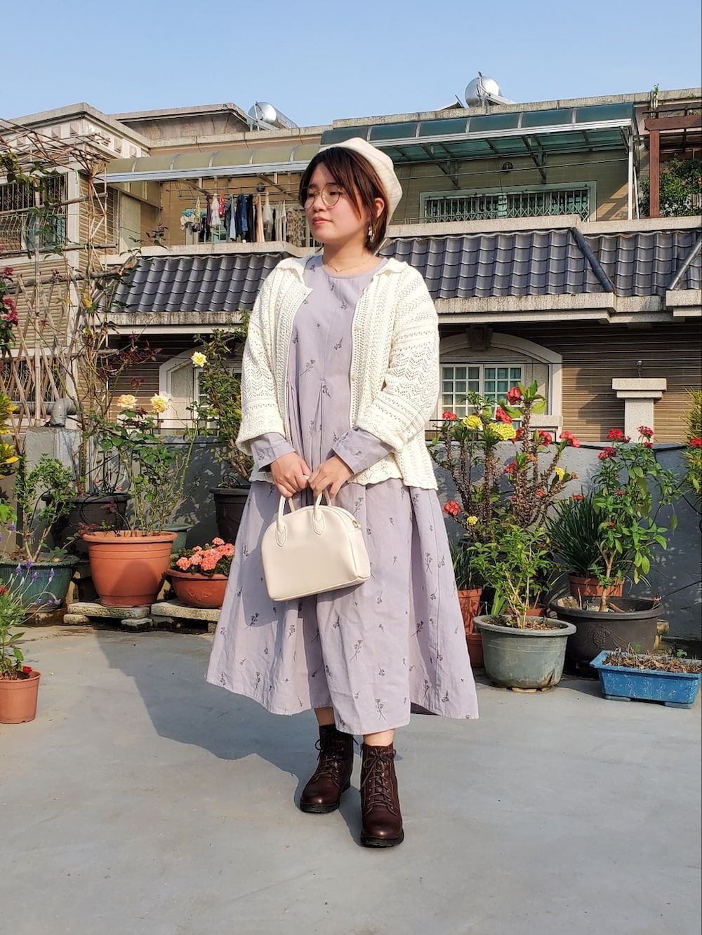 ブルー系のワンピース、ホワイト系のカーディガン/ボレロ、ブラウン系のブーツを着用したレディースの春コーディネートの2枚目の写真