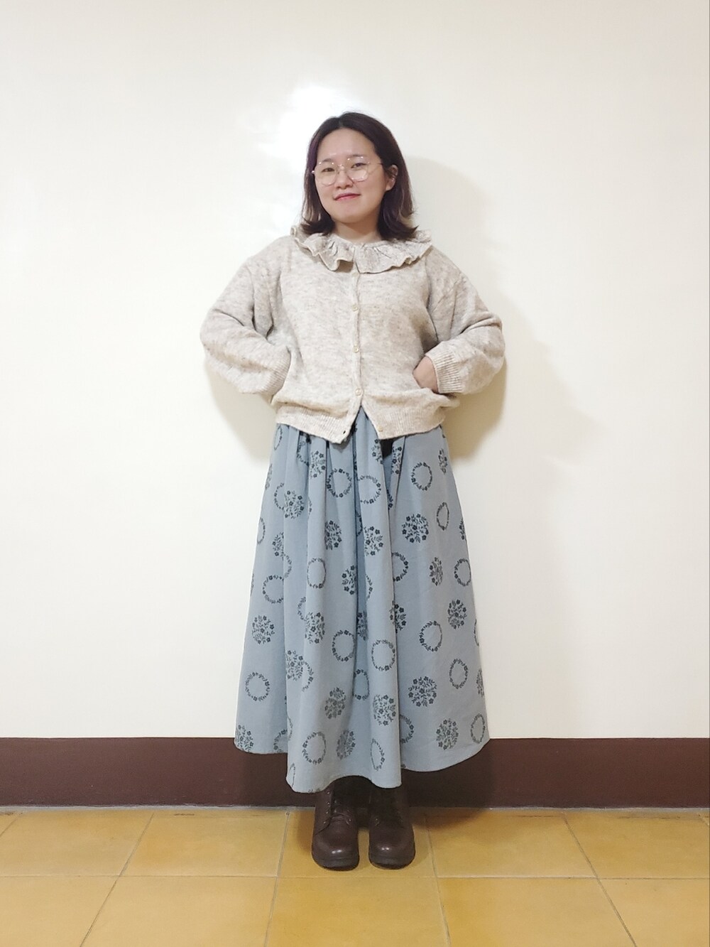 グリーン系のノーカラーコート、ホワイト系のニット/セーター、ブルー系のスカートを着用したレディースの冬コーディネートの5枚目の写真