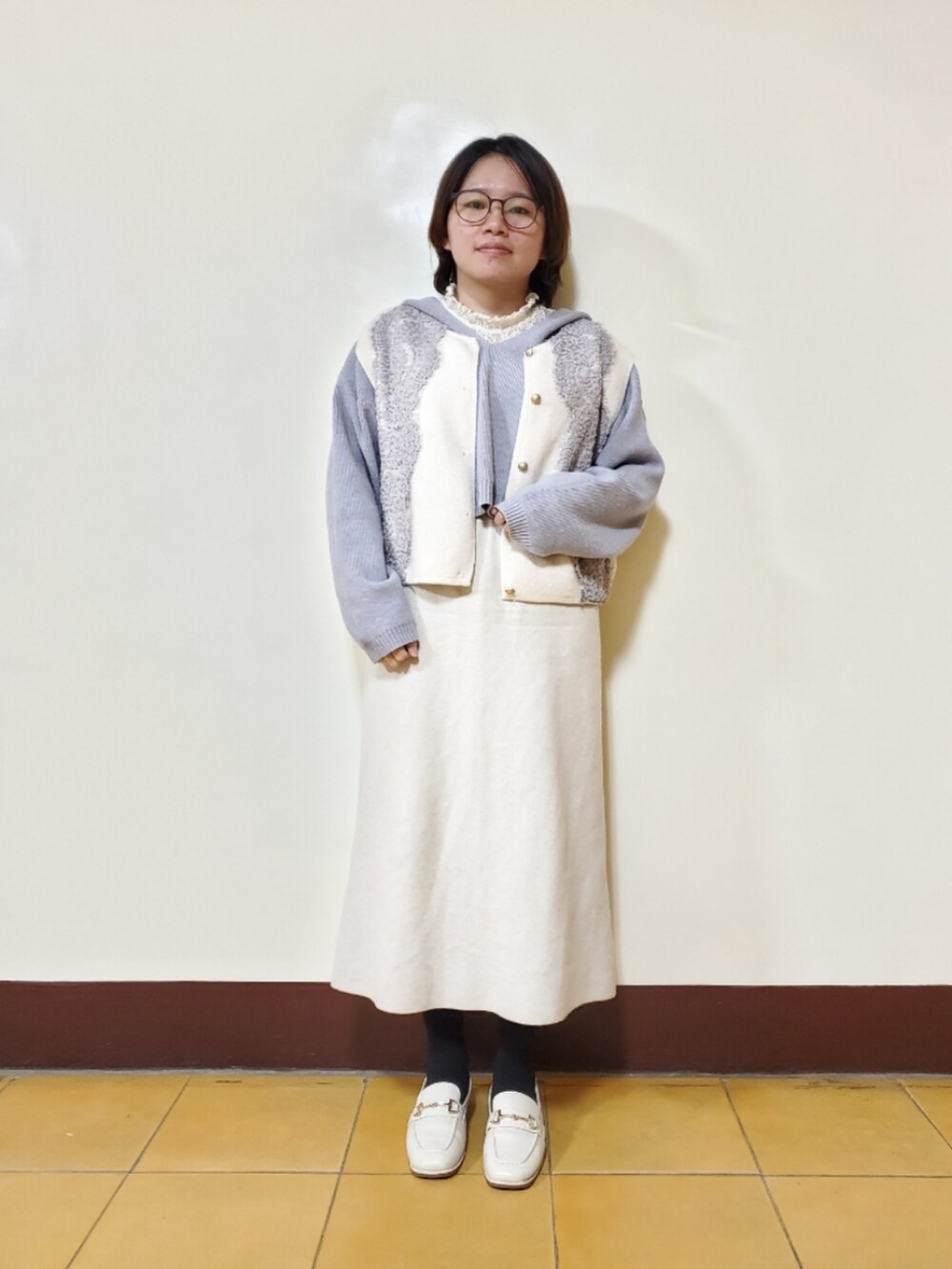 ブルー系のニット/セーター、ホワイト系のトップス、ベージュ系のスカートを着用したレディースの春コーディネートの2枚目の写真