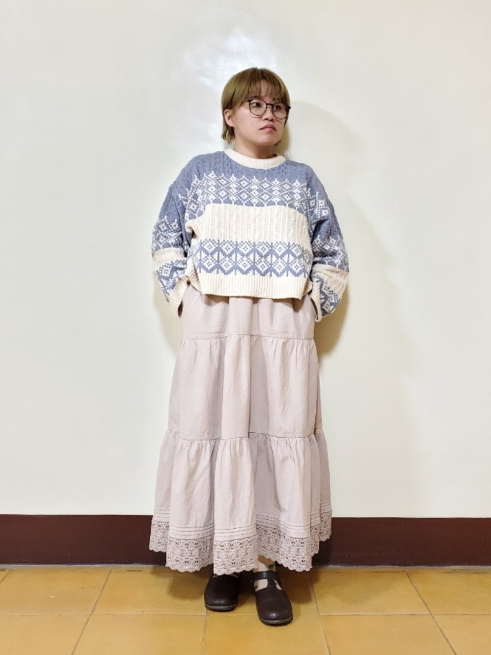 ブルー系のニット/セーター、ベージュ系のスカート、ブラウン系のドレスシューズを着用したレディースの春コーディネートの2枚目の写真