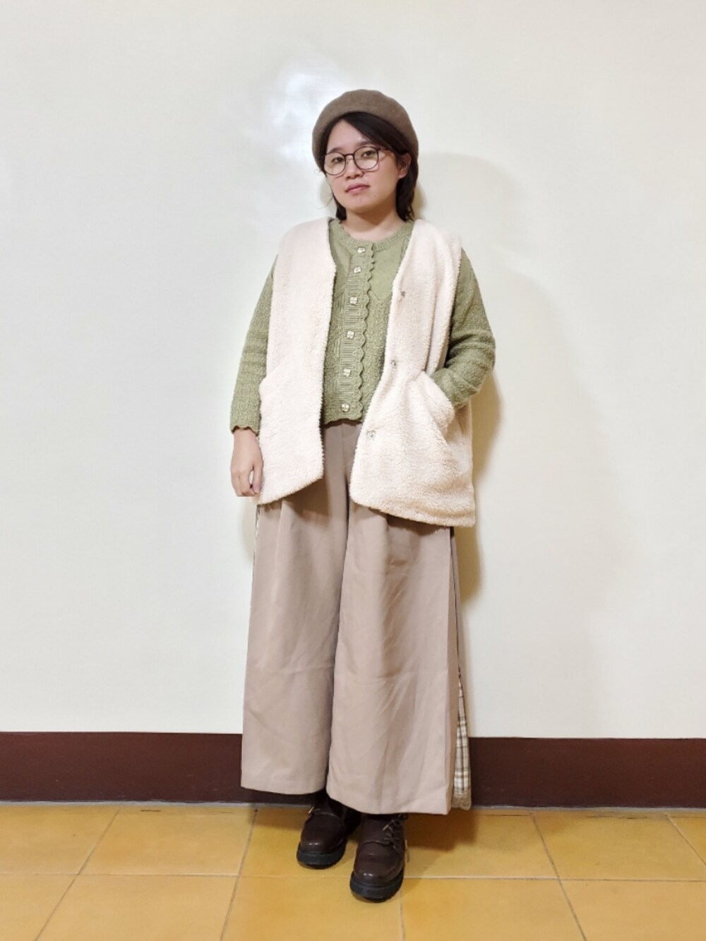 グリーン系のニット/セーター、ベージュ系のその他パンツ、ホワイト系のベストを着用したレディースの冬コーディネートの2枚目の写真