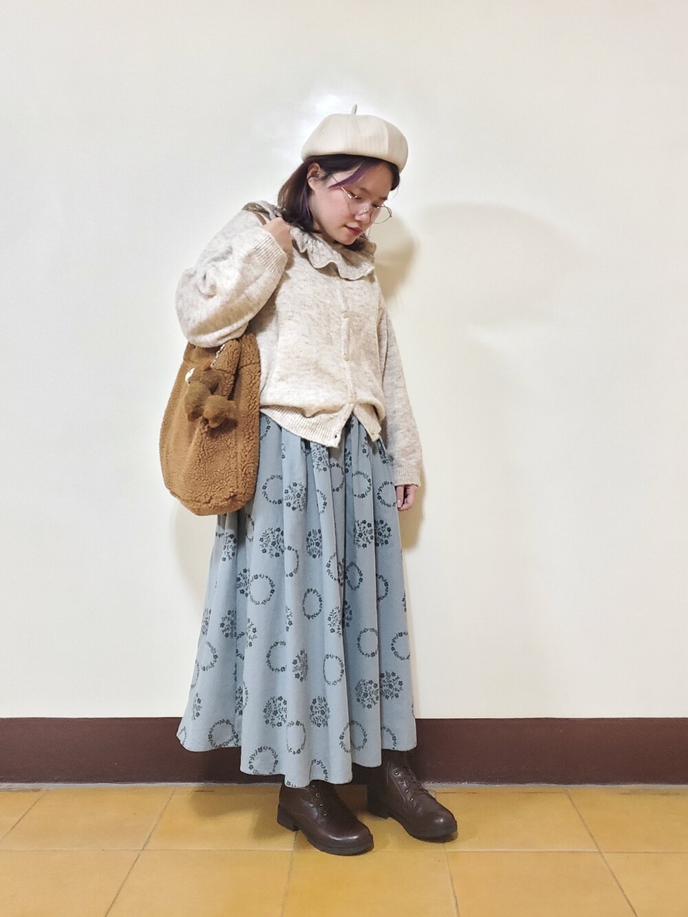 グリーン系のノーカラーコート、ホワイト系のニット/セーター、ブルー系のスカートを着用したレディースの冬コーディネートの3枚目の写真