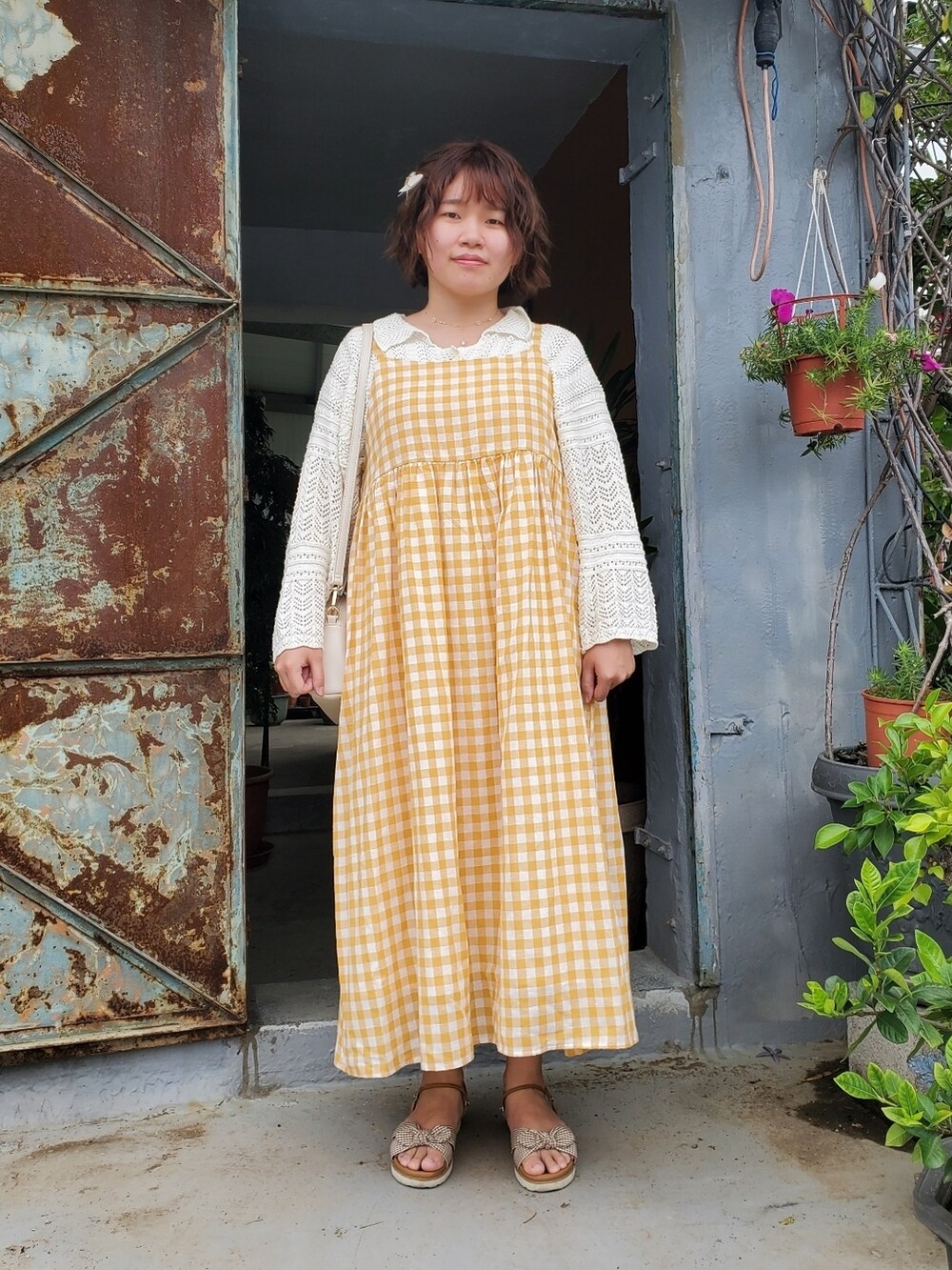 オレンジ系のワンピース、ホワイト系のカーディガン/ボレロ、ブラウン系のサンダルを着用したレディースの春コーディネートの5枚目の写真