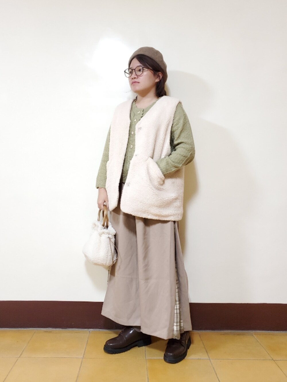 グリーン系のニット/セーター、ベージュ系のその他パンツ、ホワイト系のベストを着用したレディースの冬コーディネートの3枚目の写真