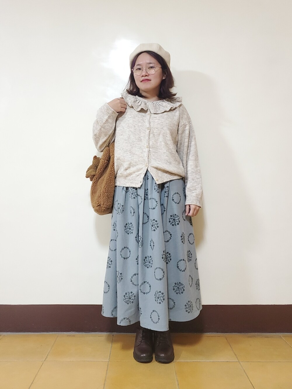 グリーン系のノーカラーコート、ホワイト系のニット/セーター、ブルー系のスカートを着用したレディースの冬コーディネートの4枚目の写真