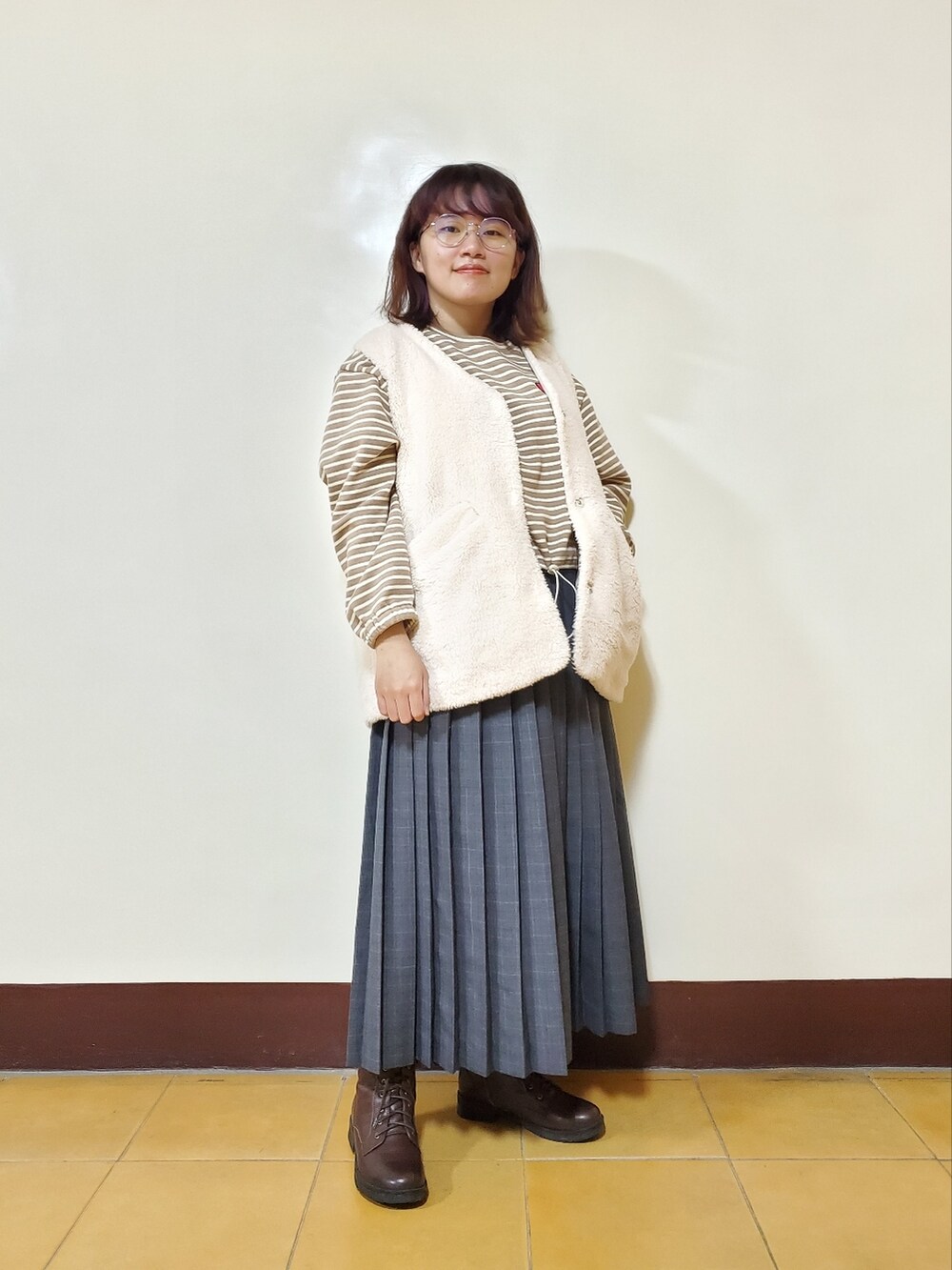 オレンジ系のその他アウター、ホワイト系のベスト、ベージュ系のTシャツ/カットソーを着用したレディースの冬コーディネートの4枚目の写真