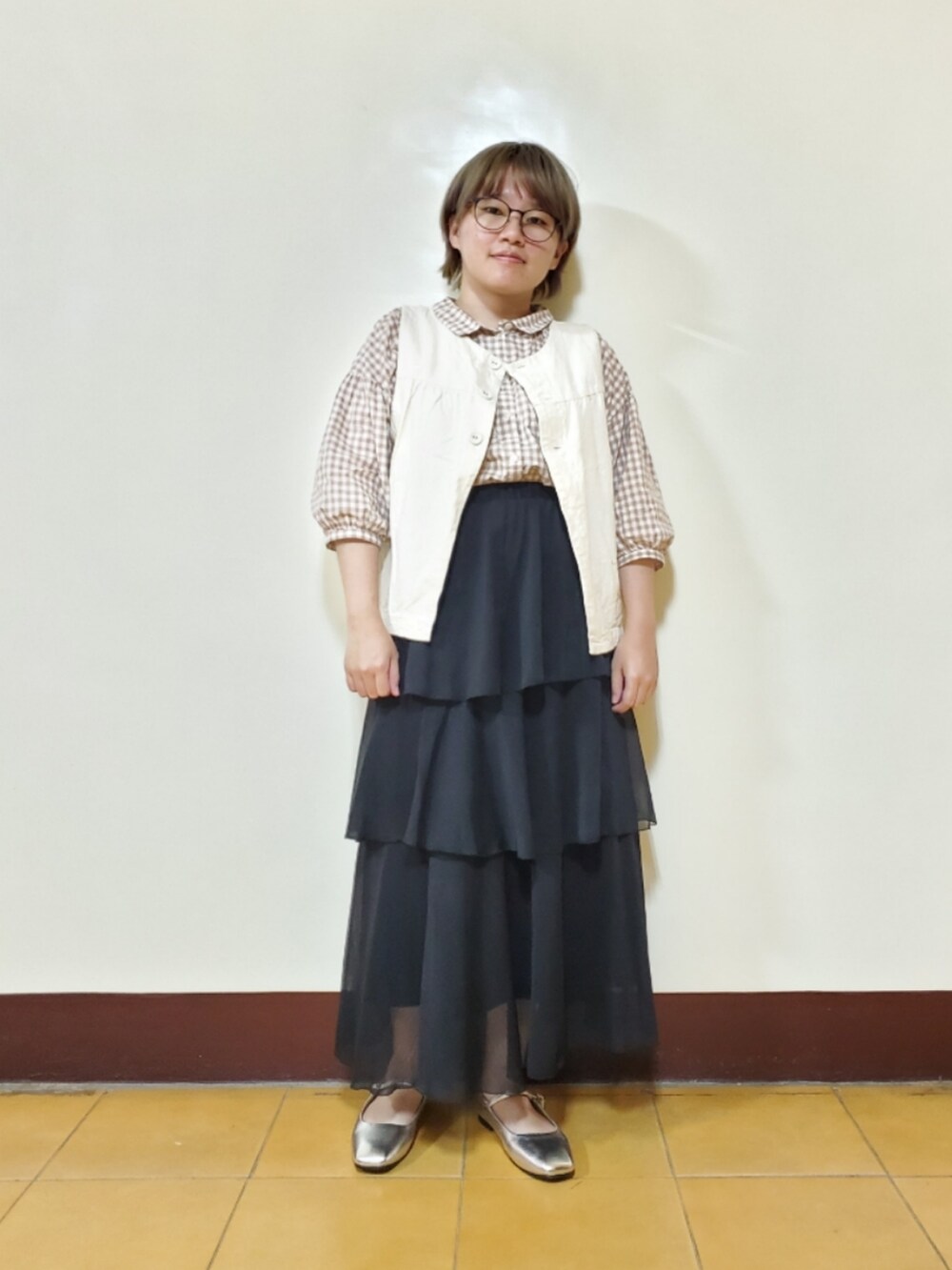 ベージュ系のシャツ/ブラウス、ブラック系のスカート、ホワイト系のベストを着用したレディースの春コーディネートの2枚目の写真