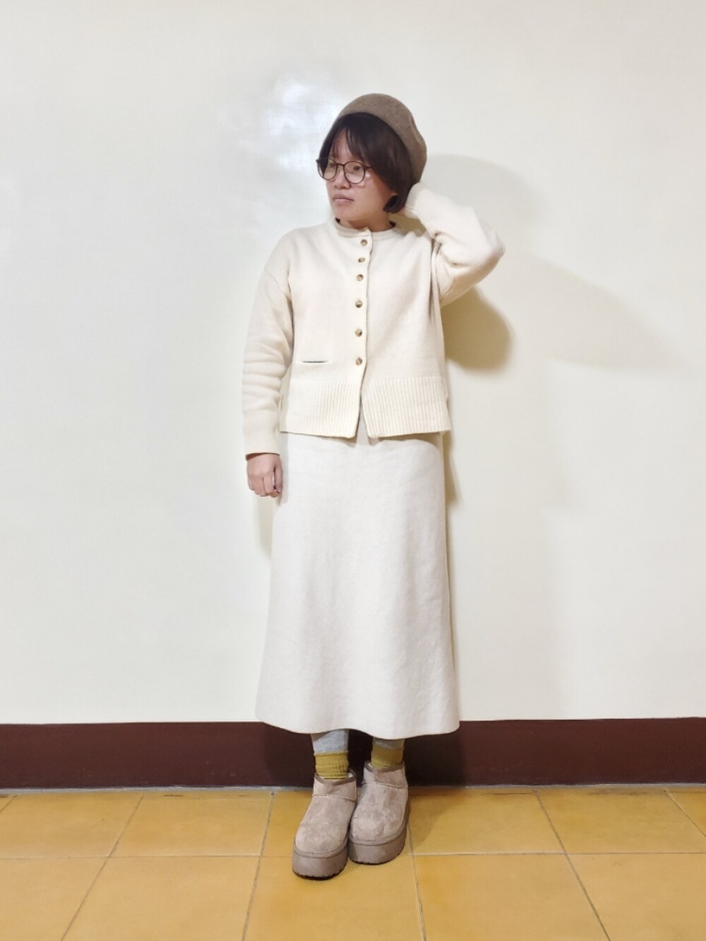 ホワイト系のカーディガン/ボレロ、ベージュ系のスカート、ブラウン系のブーツを着用したレディースの冬コーディネートの3枚目の写真