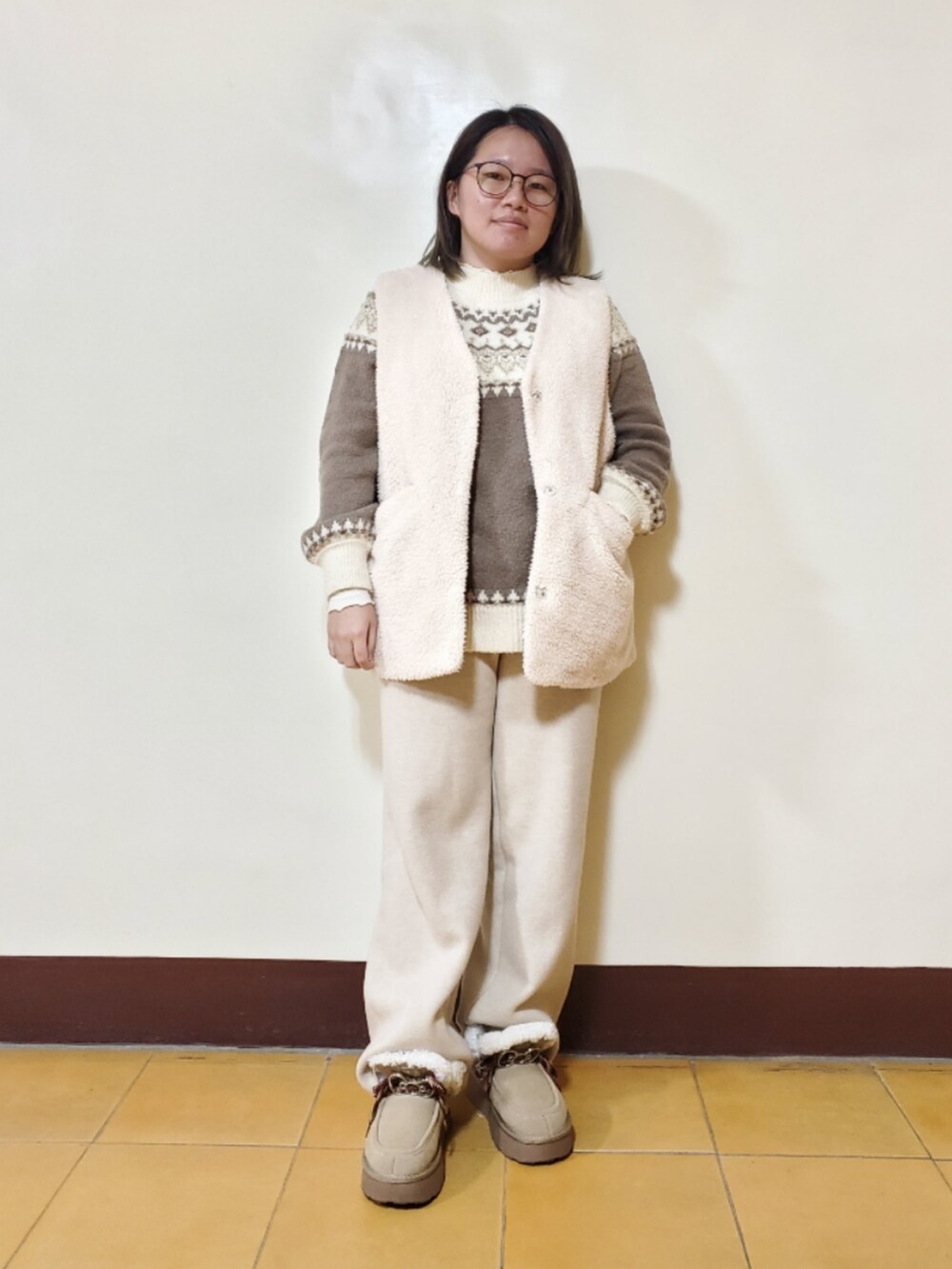 ベージュ系のニット/セーター、ホワイト系のベスト、ベージュ系のチノパンツを着用したレディースの冬コーディネートの2枚目の写真