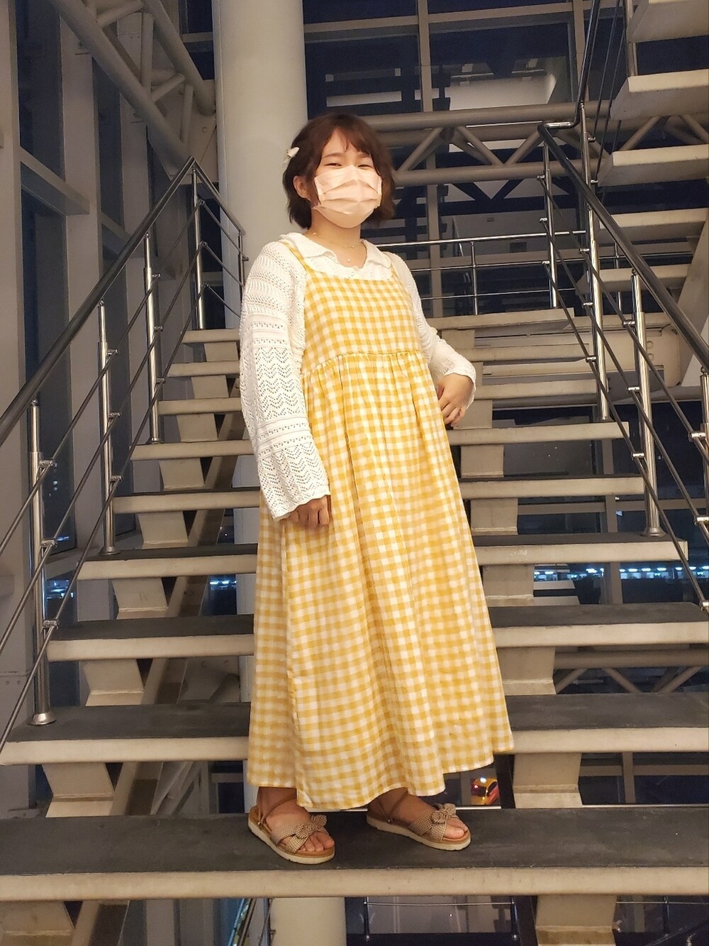 オレンジ系のワンピース、ホワイト系のカーディガン/ボレロ、ブラウン系のサンダルを着用したレディースの春コーディネートの2枚目の写真