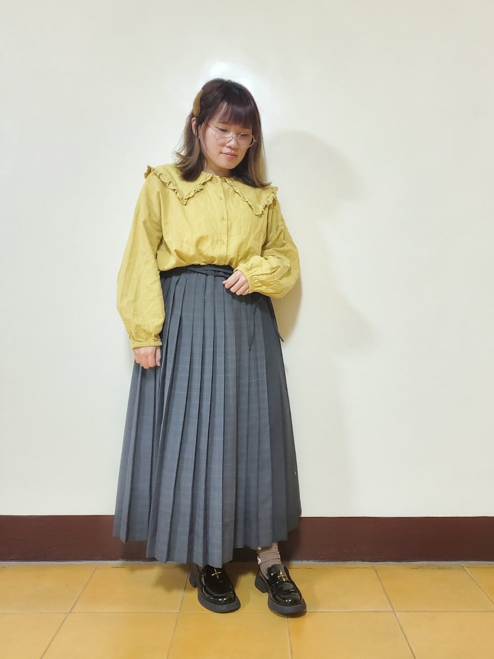 ホワイト系のノーカラージャケット、イエロー系のチュニック、グレー系のスカートを着用したレディースの春コーディネートの2枚目の写真