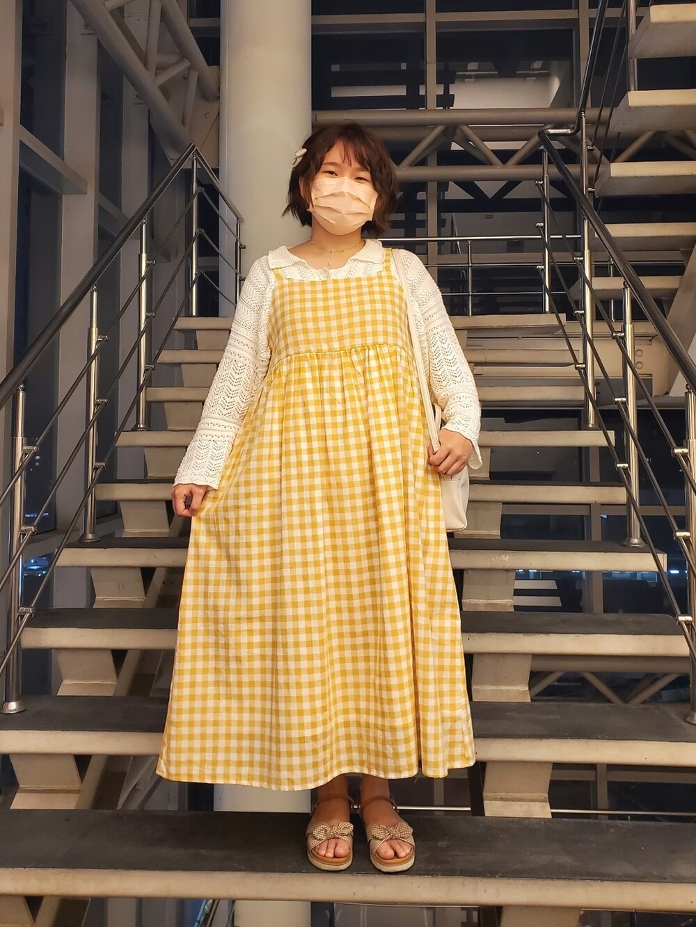 オレンジ系のワンピース、ホワイト系のカーディガン/ボレロ、ブラウン系のサンダルを着用したレディースの春コーディネートの3枚目の写真