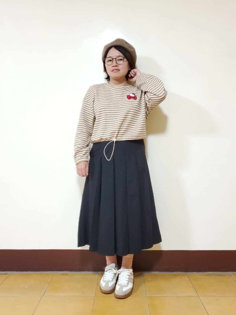 ベージュ系のTシャツ/カットソー、ブラック系のスカート、ベージュ系のスニーカーを着用したレディースの春コーディネートの2枚目の写真