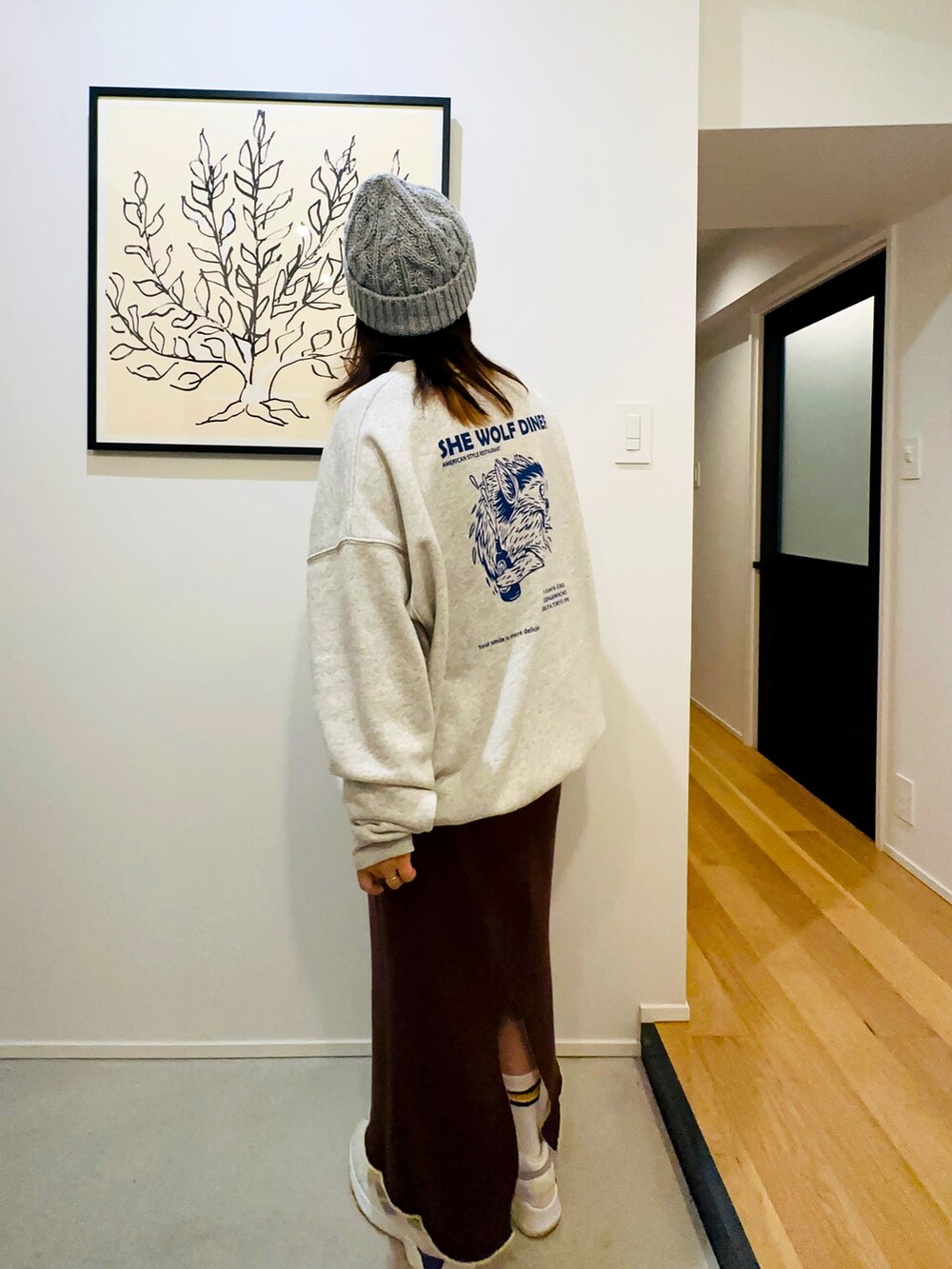 グレー系のスウェット、イエロー系のスカート、ホワイト系のスニーカーを着用したレディースの冬コーディネートの2枚目の写真