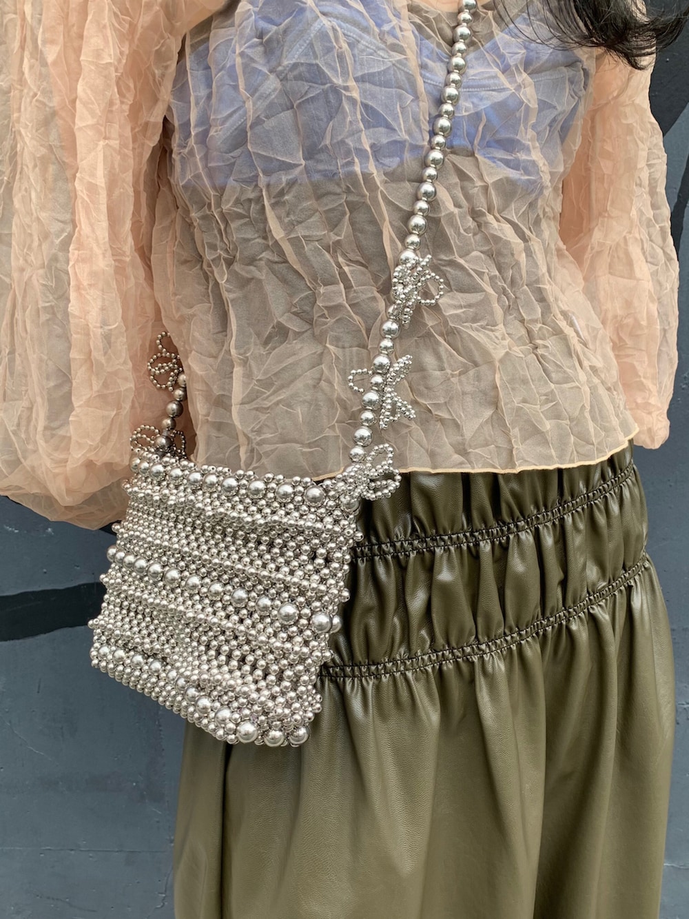 シルバー系のショルダーバッグ、シルバー系のローファーを着用したレディースの夏コーディネートの2枚目の写真