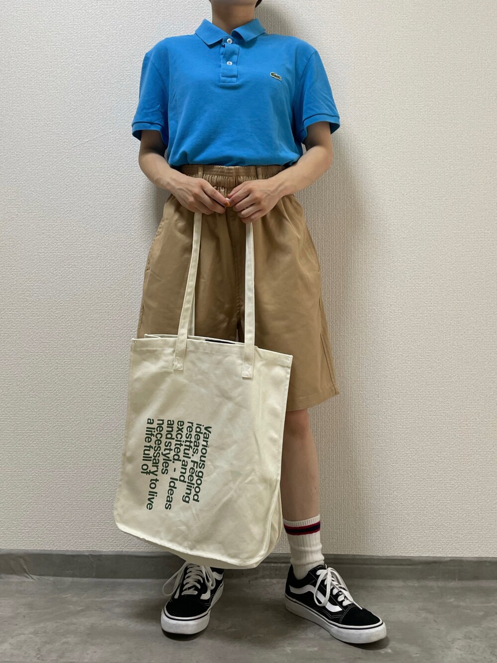 ブルー系のポロシャツ、ベージュ系のチノパンツ、ブラック系のスニーカーを着用したレディースの夏コーディネートの2枚目の写真