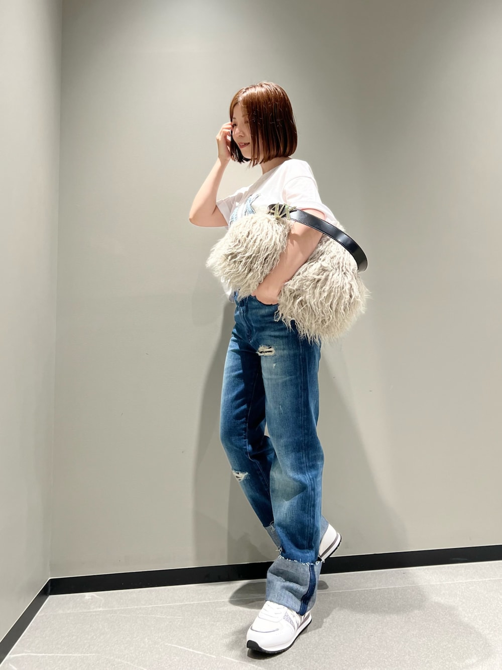 ホワイト系のTシャツ/カットソー、ブルー系のデニムパンツ、ベージュ系のハンドバッグを着用したレディースの秋コーディネートの2枚目の写真