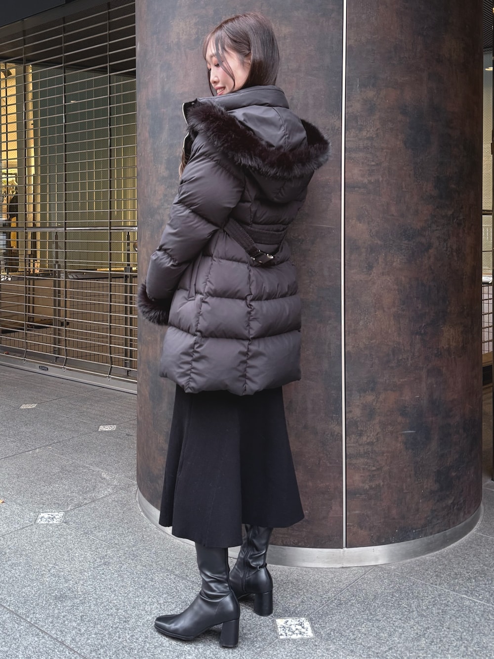 ブラック系のダウンジャケット/コート、ブラック系のブーツ、ブラック系のワンピースを着用したレディースの冬コーディネートの3枚目の写真