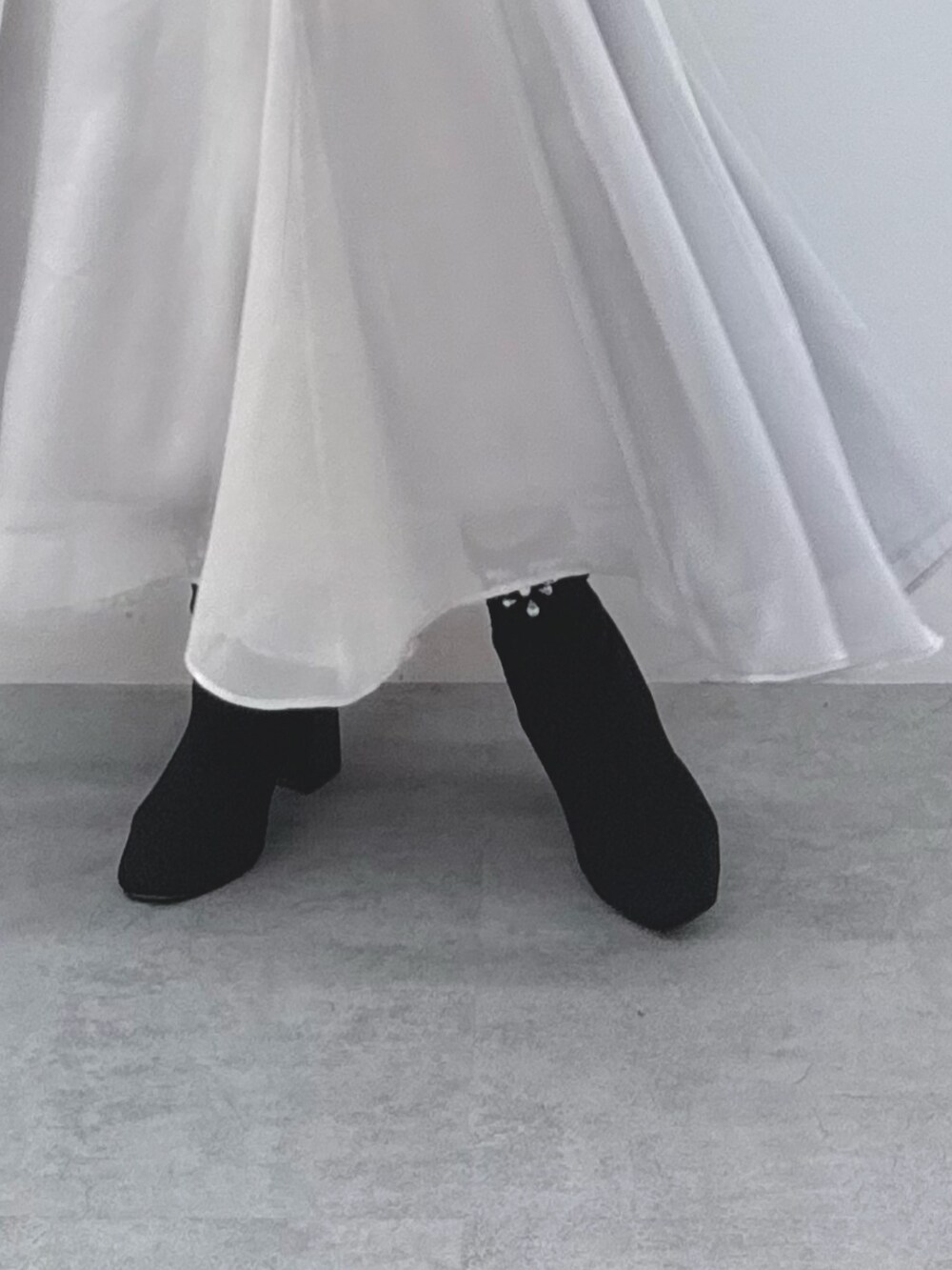 グレー系のスカート、ブラック系のブーツ、グレー系のムートンコートを着用したレディースの秋コーディネートの7枚目の写真