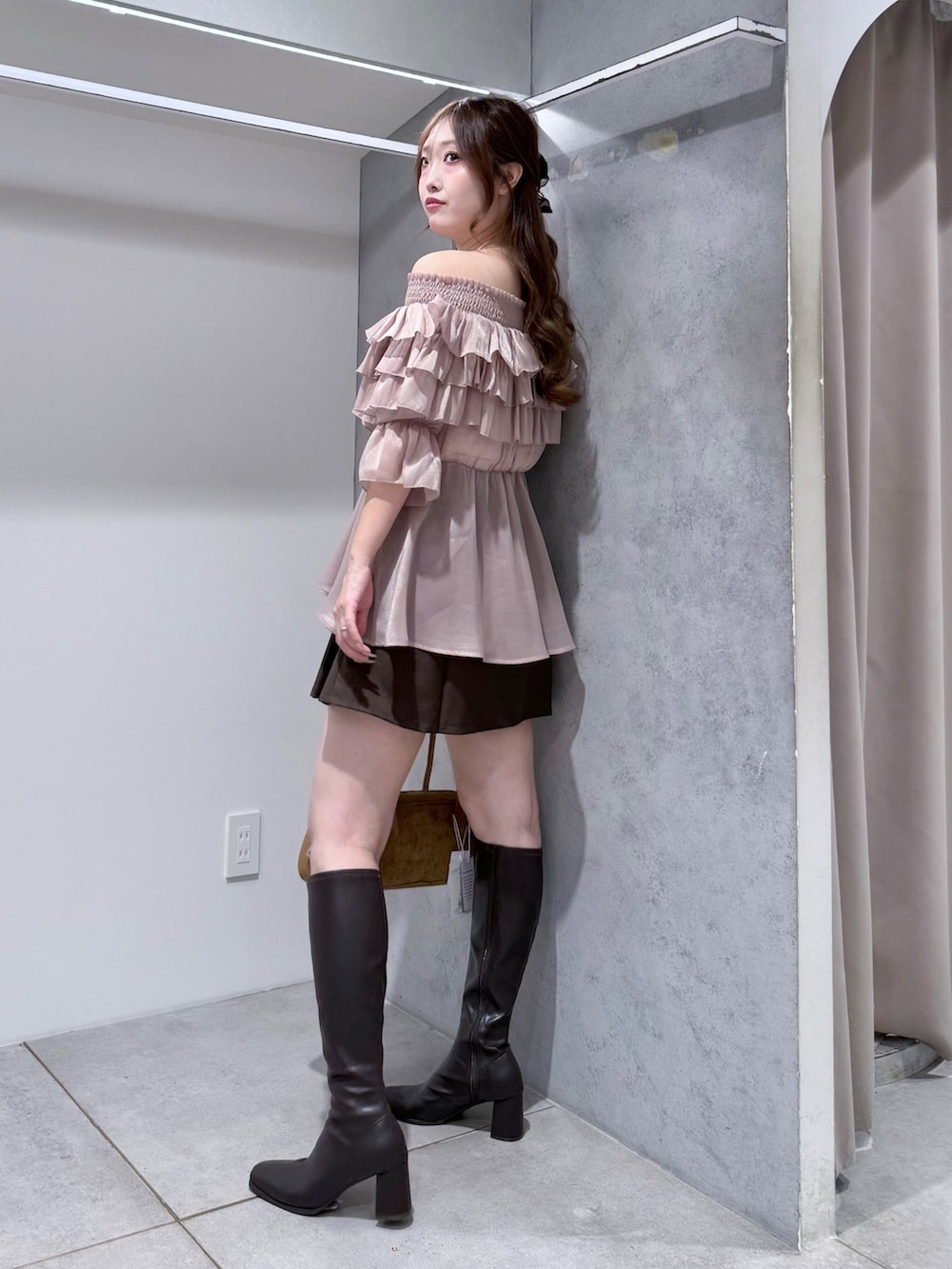 ピンク系のシャツ/ブラウス、ブラウン系のハンドバッグ、ブラウン系のブーツを着用したレディースの秋コーディネートの2枚目の写真