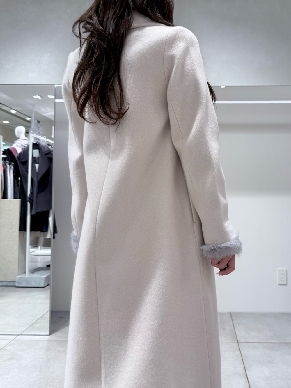 ホワイト系のチェスターコート、ホワイト系のスカート、グレー系のニット/セーターを着用したレディースの冬コーディネートの6枚目の写真