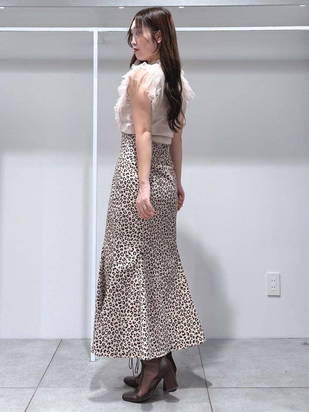 ピンク系のニット/セーター、ベージュ系のスカート、ブラウン系のブーツを着用したレディースの夏コーディネートの3枚目の写真