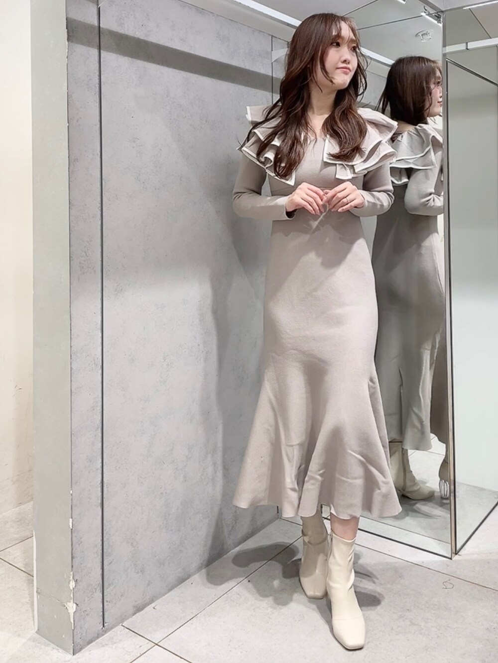 ベージュ系のワンピース、ホワイト系のブーツを着用したレディースの秋コーディネートの2枚目の写真