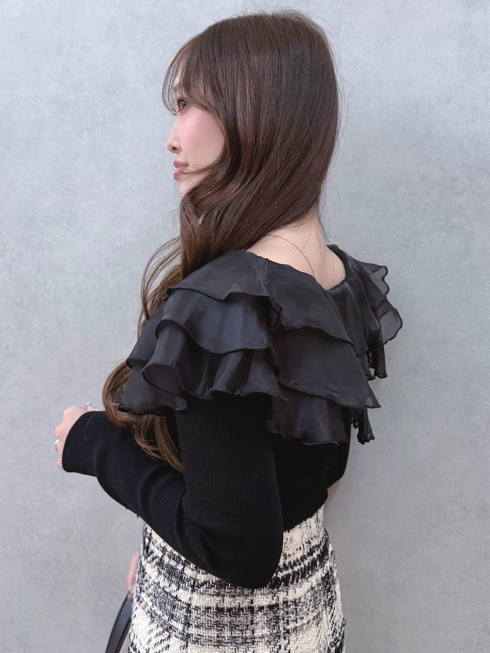 ブラック系のニット/セーター、ホワイト系のスカート、ブラック系のブーツを着用したレディースの冬コーディネートの5枚目の写真