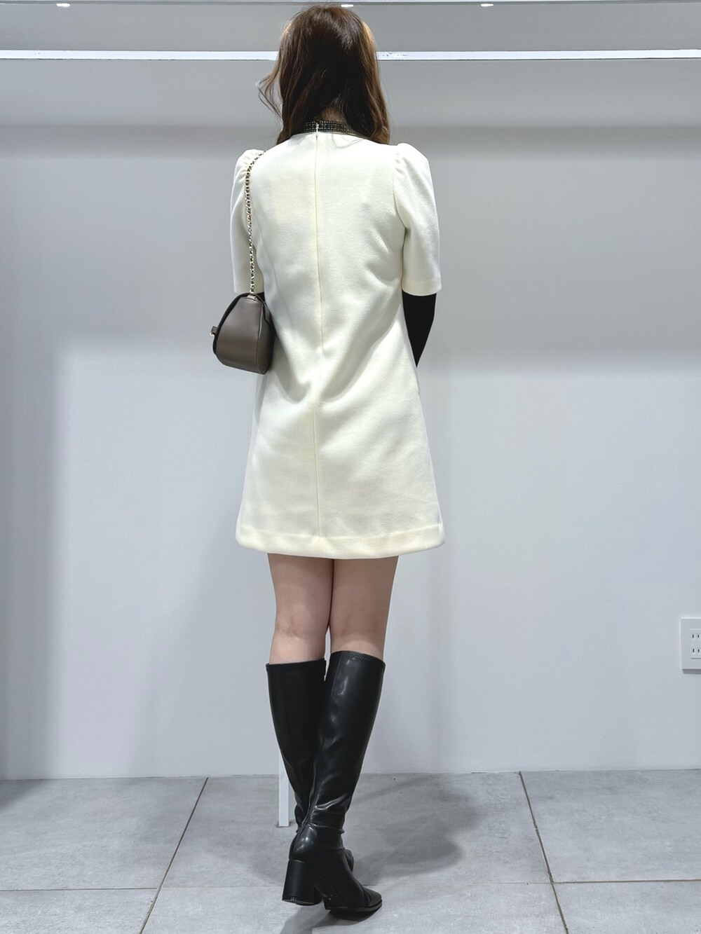 ホワイト系のワンピース、ブラック系のニット/セーター、ブラウン系のハンドバッグを着用したレディースの秋コーディネートの4枚目の写真