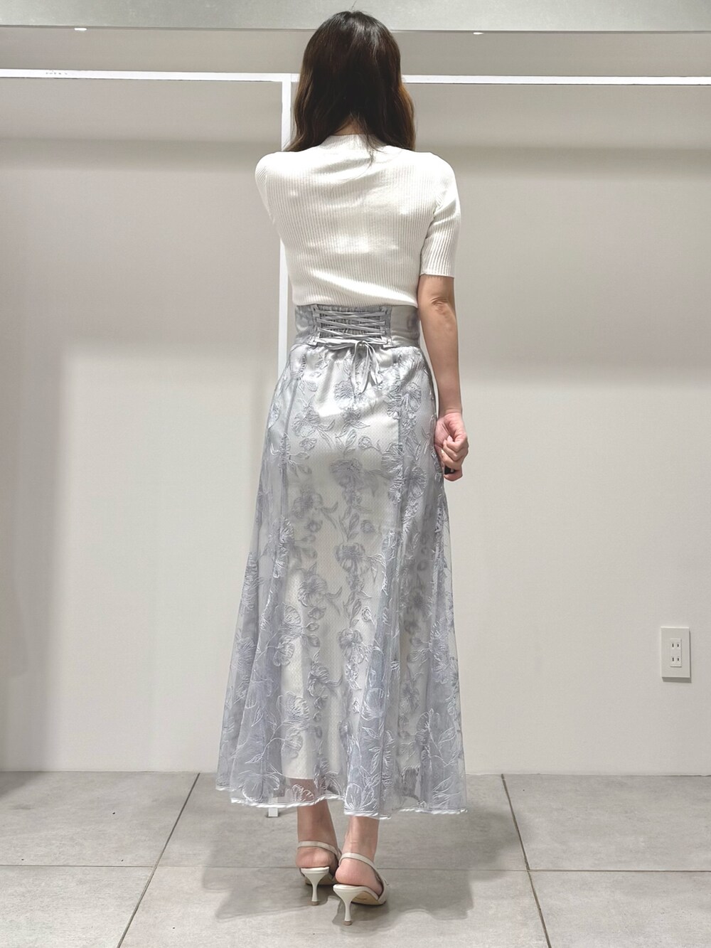 ホワイト系のニット/セーター、ブルー系のスカート、ホワイト系のパンプスを着用したレディースの春コーディネートの4枚目の写真