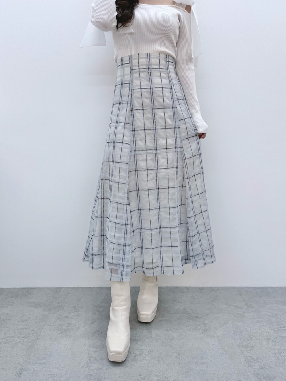 ホワイト系のニット/セーター、ブルー系のスカート、ホワイト系のブーツを着用したレディースの冬コーディネートの8枚目の写真