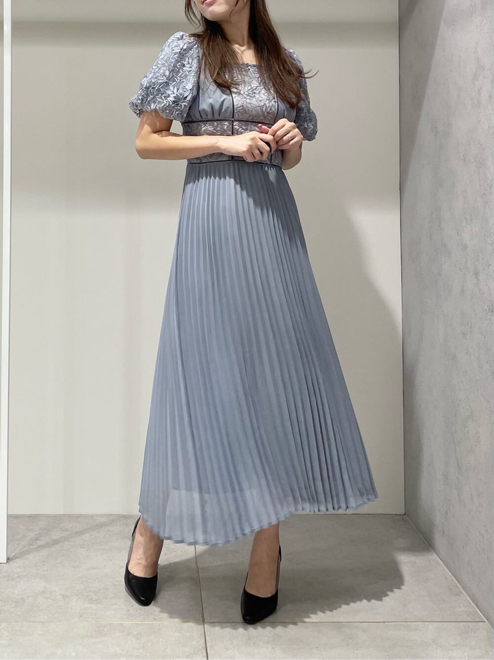 ブラック系のパンプス、ブルー系のワンピース、シルバー系のイヤリングを着用したレディースの秋コーディネートの3枚目の写真