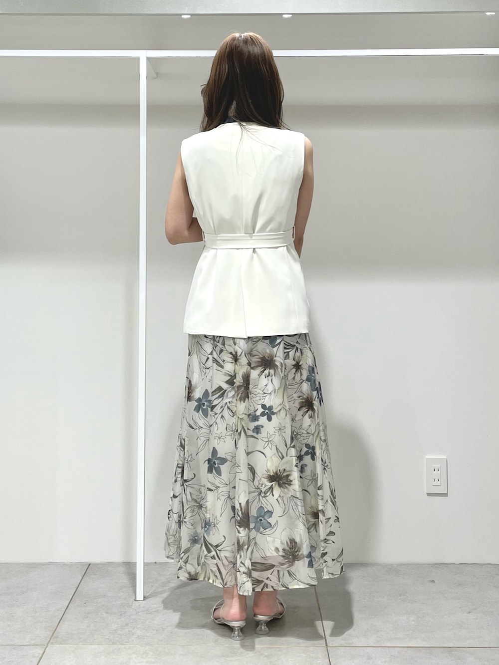 ホワイト系のベスト、グリーン系のスカート、ブルー系のニット/セーターを着用したレディースの春コーディネートの3枚目の写真