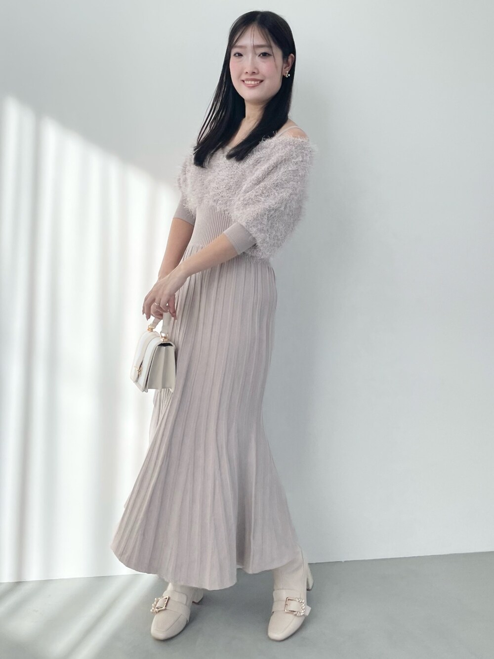 ベージュ系のワンピース、ホワイト系のハンドバッグ、ホワイト系のブーツを着用したレディースの春コーディネートの2枚目の写真