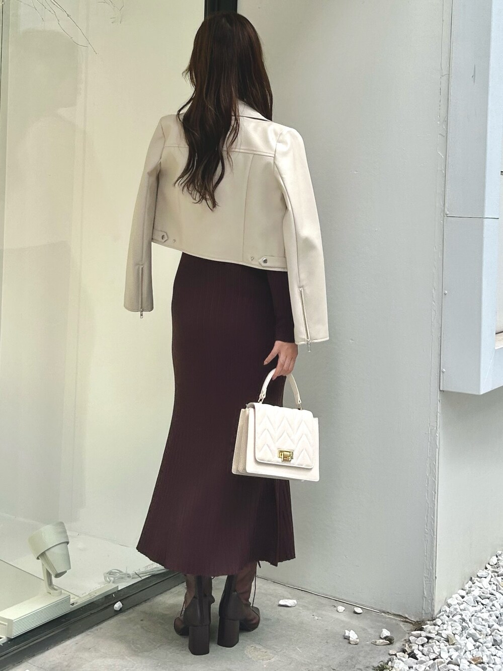 ホワイト系のライダースジャケット、ブラウン系のワンピース、ホワイト系のショルダーバッグを着用したレディースの夏コーディネートの3枚目の写真