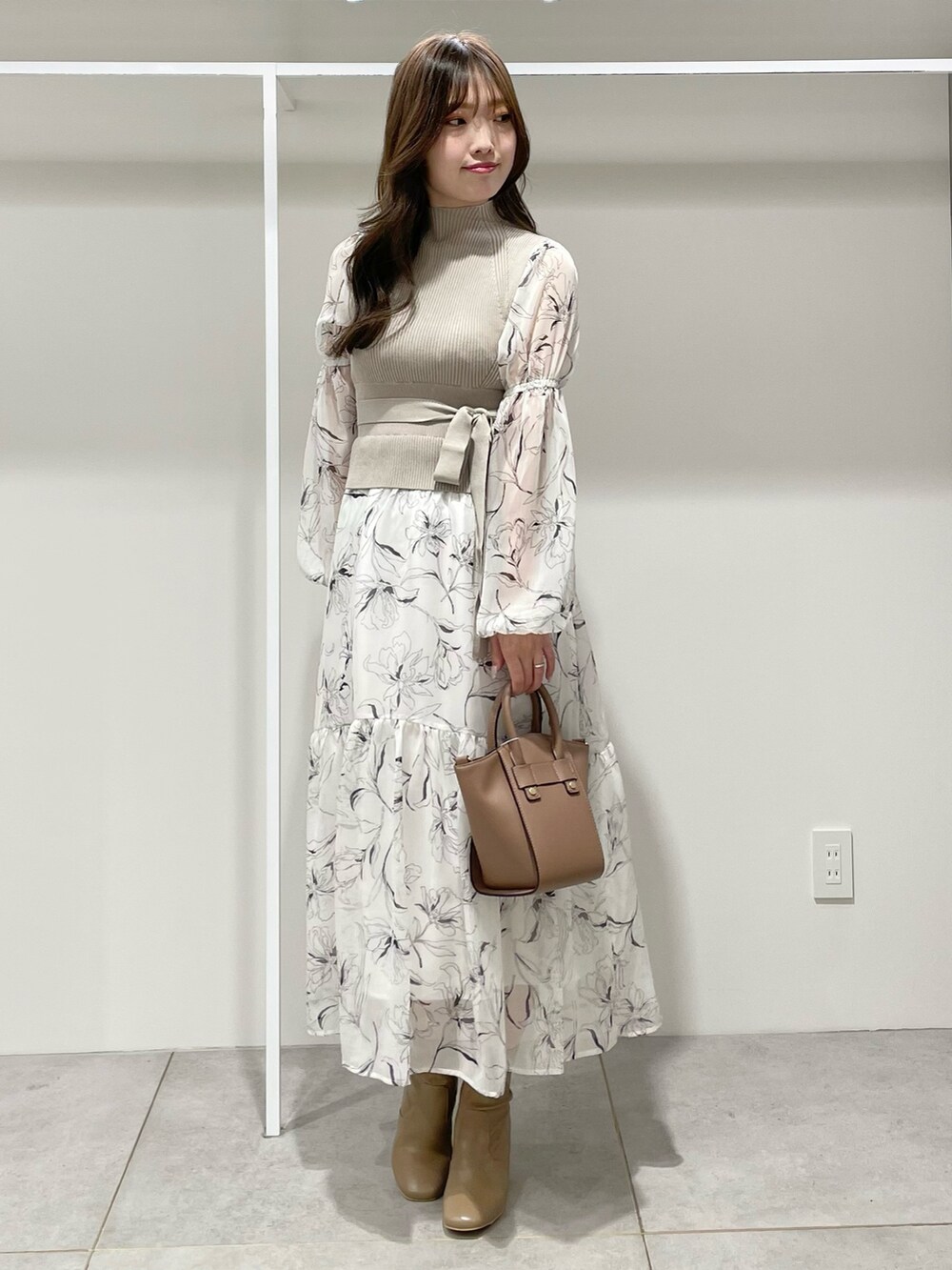 ホワイト系のワンピース、ブラウン系のハンドバッグ、ブラウン系のブーツを着用したレディースの秋コーディネートの2枚目の写真