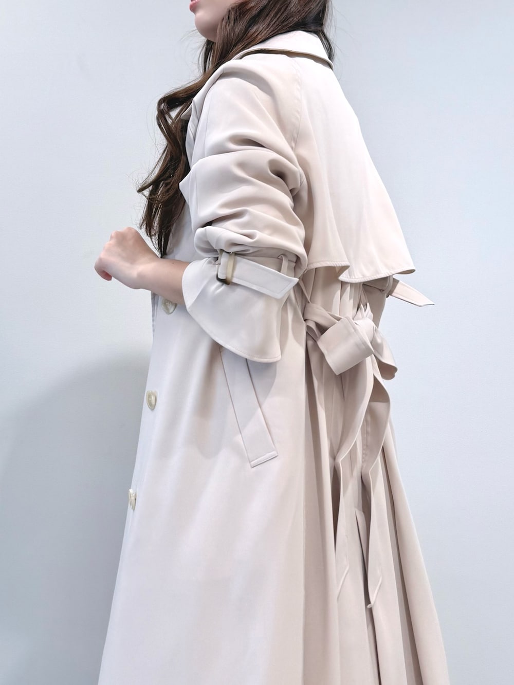 ベージュ系のワンピース、ホワイト系のパンプス、ホワイト系のトレンチコートを着用したレディースの冬コーディネートの6枚目の写真