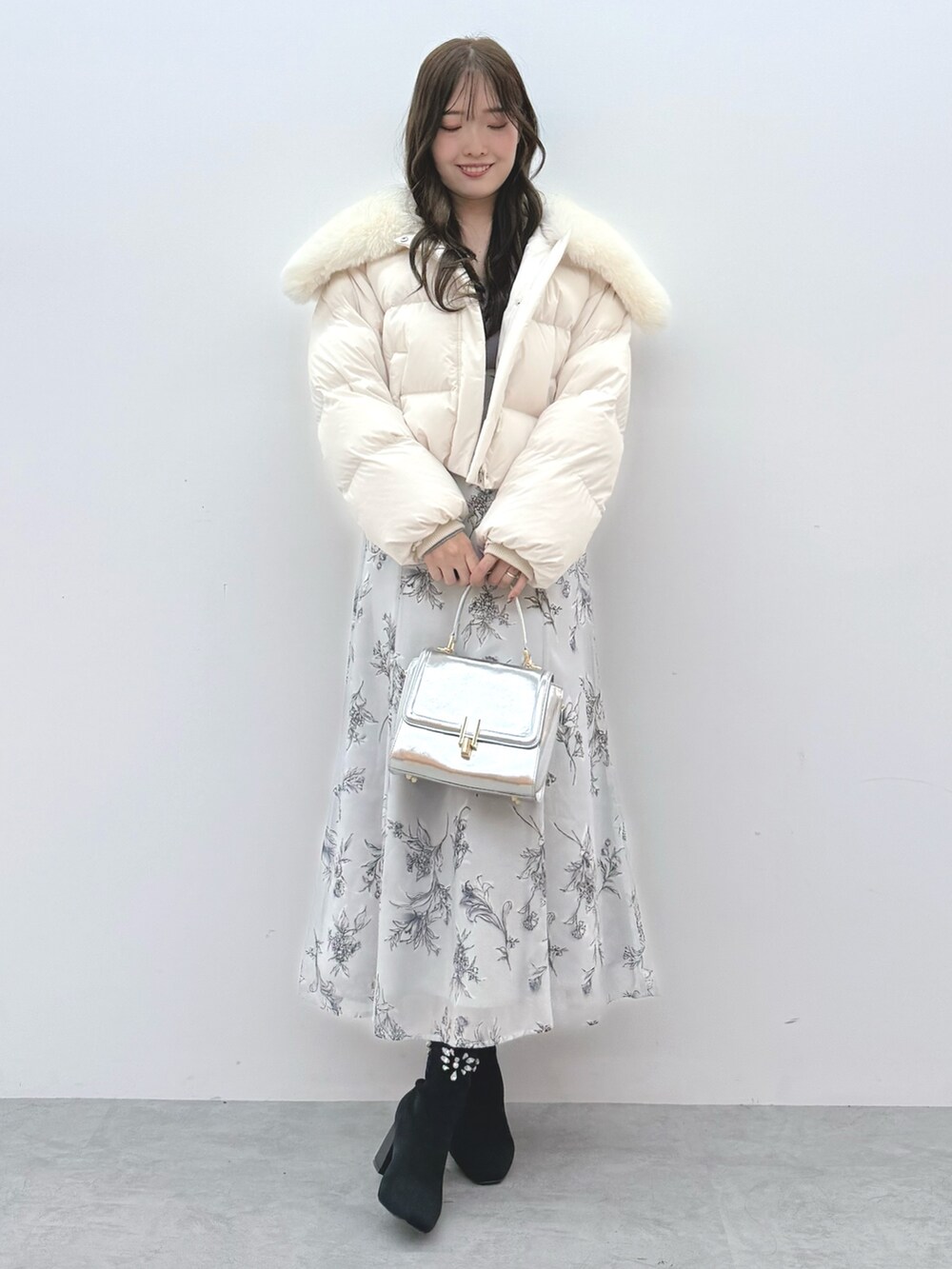 ホワイト系のダウンジャケット/コート、シルバー系のハンドバッグ、ブラック系のブーツを着用したレディースの秋コーディネートの2枚目の写真