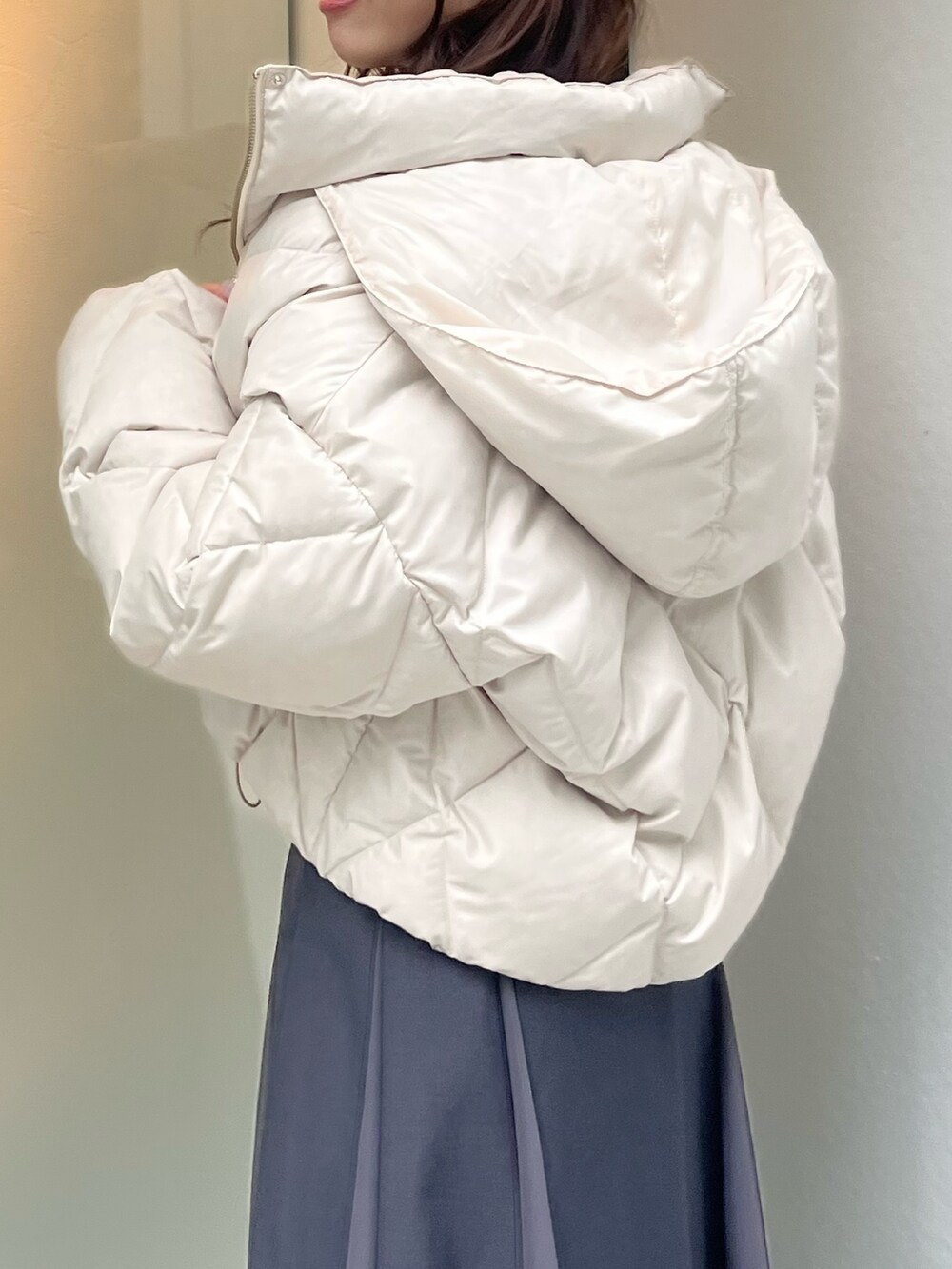 ホワイト系のダウンジャケット/コート、ブルー系のニット/セーター、グレー系のスカートを着用したレディースの秋コーディネートの4枚目の写真