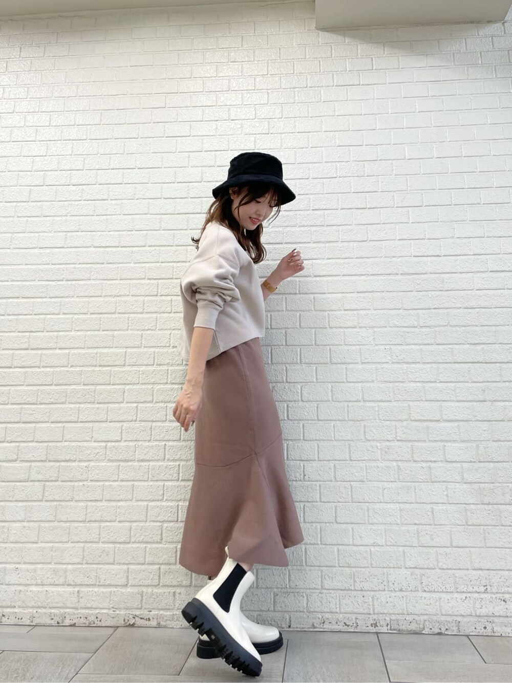 ベージュ系のTシャツ/カットソー、ブラウン系のワンピース、ホワイト系のブーツを着用したレディースの秋コーディネートの2枚目の写真