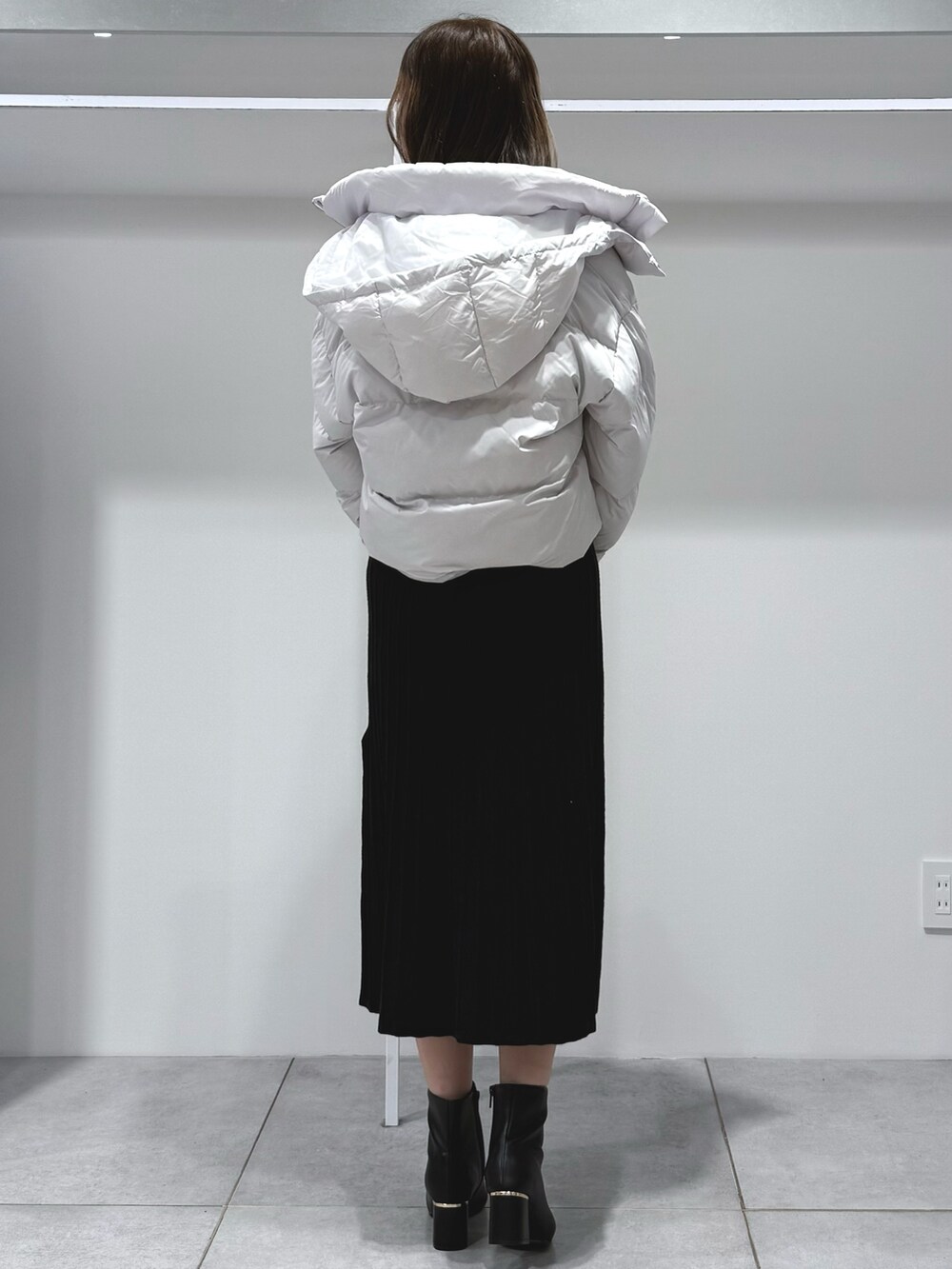 ブラック系のワンピース、ホワイト系のハンドバッグ、ブラック系のブーツを着用したレディースの秋コーディネートの4枚目の写真