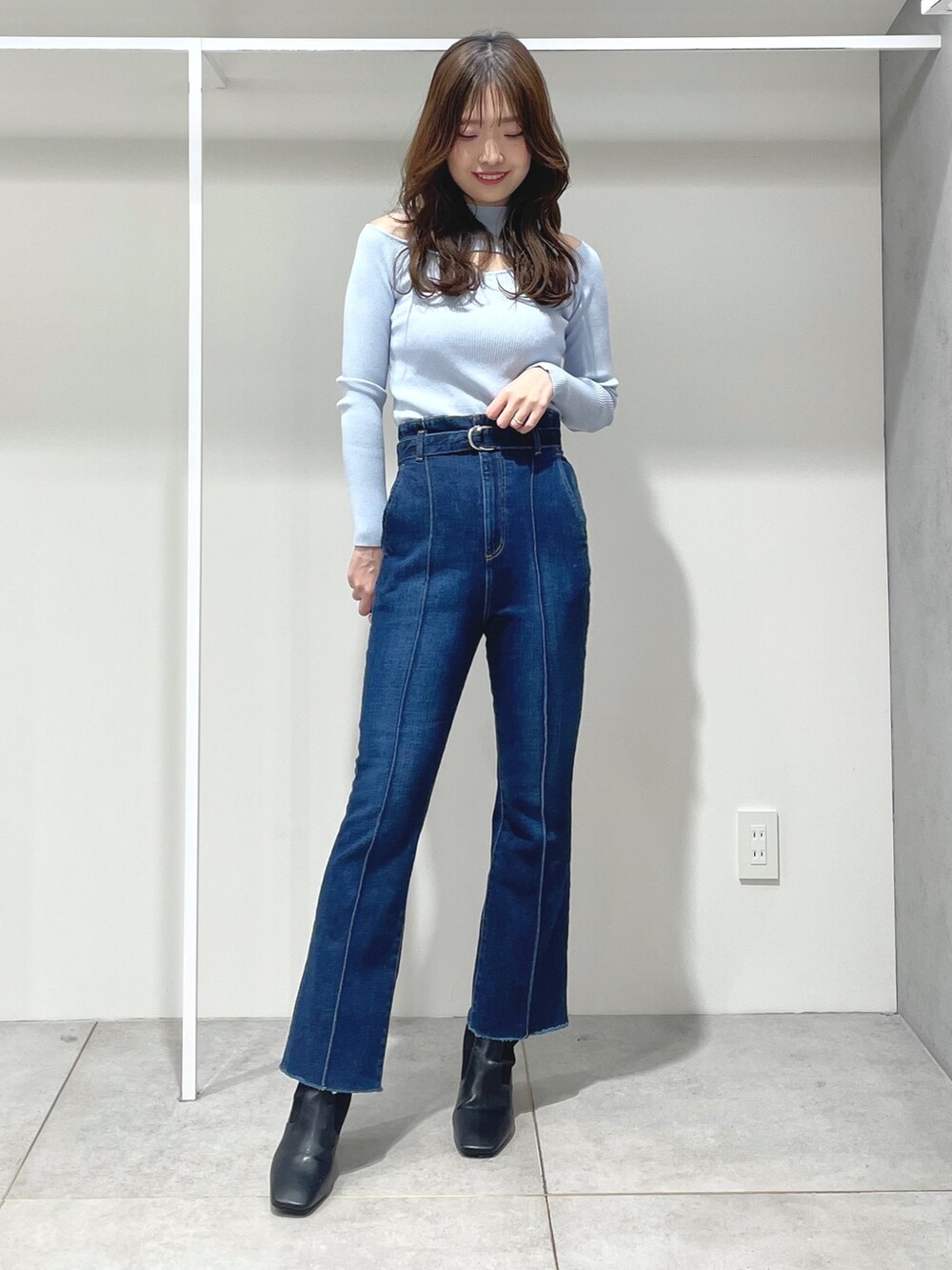 ホワイト系のハンドバッグ、ブラック系のブーツ、ブルー系のニット/セーターを着用したレディースの冬コーディネートの7枚目の写真