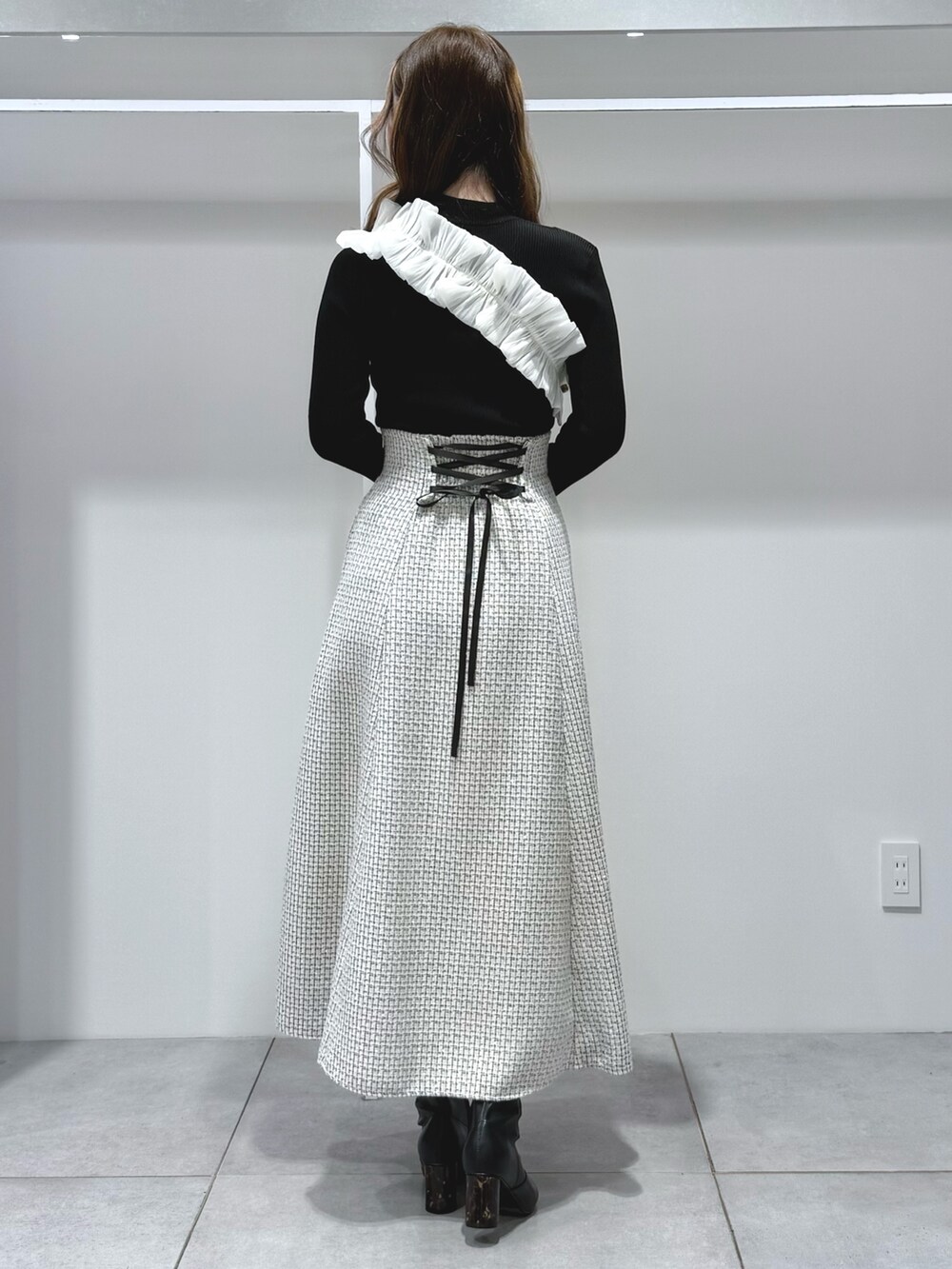 ブラック系のニット/セーター、ブラック系のハンドバッグ、ブラック系のブーツを着用したレディースの秋コーディネートの4枚目の写真