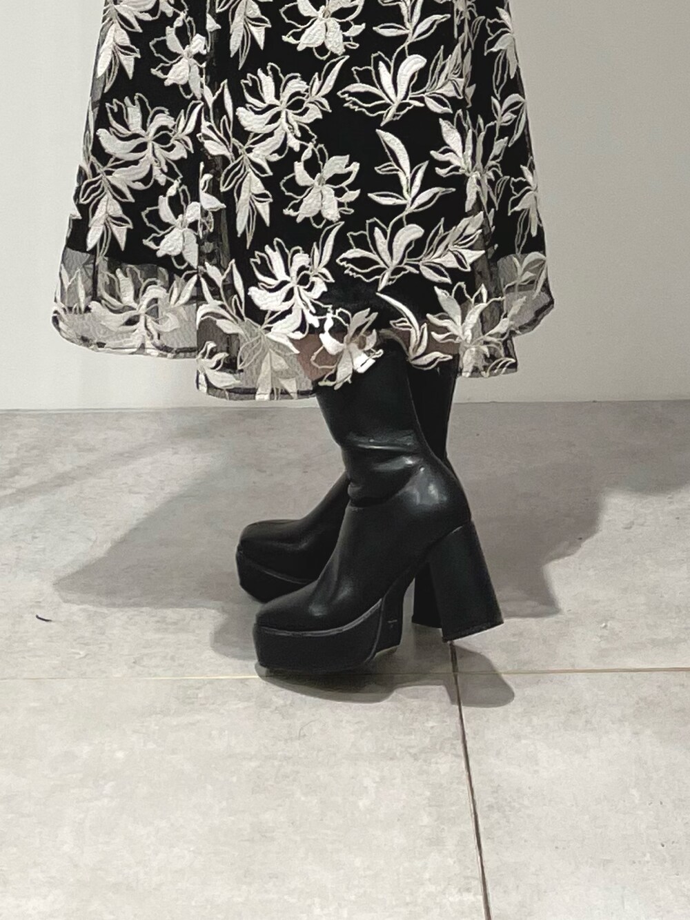 ブラック系のスカート、ブラック系のブーツ、グレー系のニット/セーターを着用したレディースの冬コーディネートの9枚目の写真