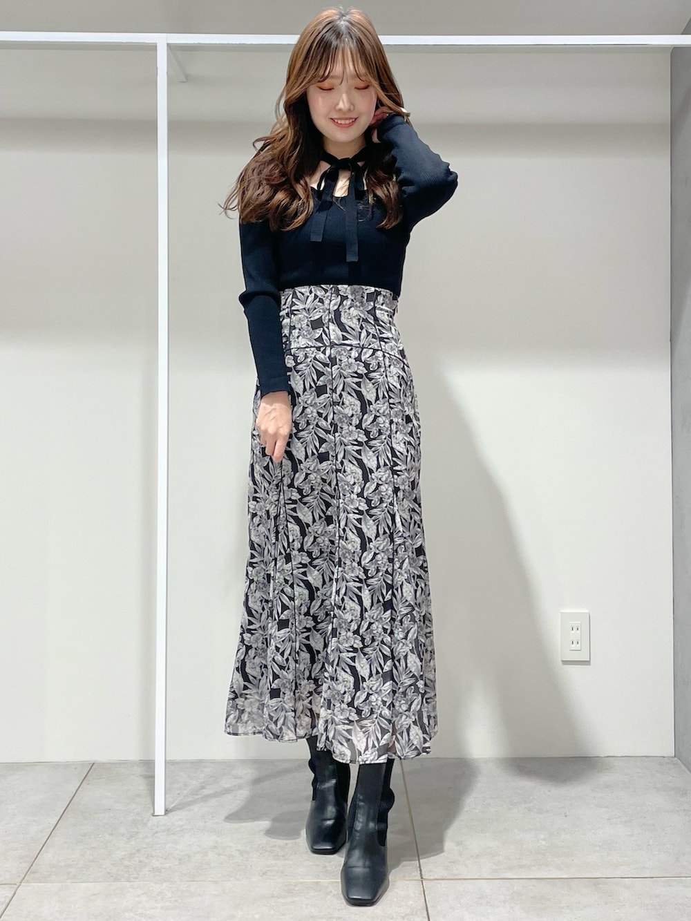 ベージュ系のチェスターコート、ブラック系のブーツ、ブラック系のスカートを着用したレディースの冬コーディネートの4枚目の写真