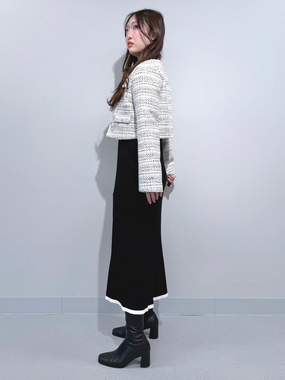 ホワイト系のテーラードジャケット、ブラック系のワンピース、ブラック系のブーツを着用したレディースの冬コーディネートの2枚目の写真