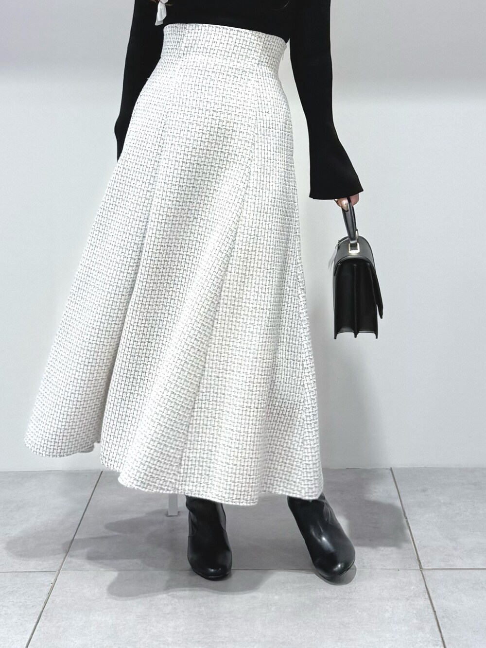 ブラック系のニット/セーター、ブラック系のハンドバッグ、ブラック系のブーツを着用したレディースの秋コーディネートの8枚目の写真