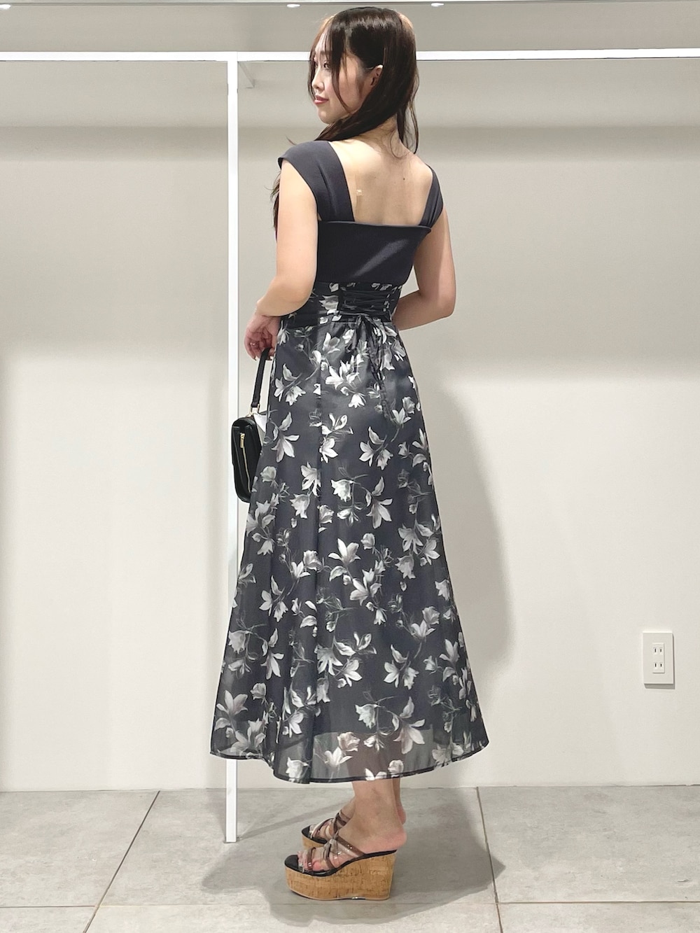 ブラック系のショルダーバッグ、ブラック系のサンダル、グレー系のワンピースを着用したレディースの夏コーディネートの3枚目の写真