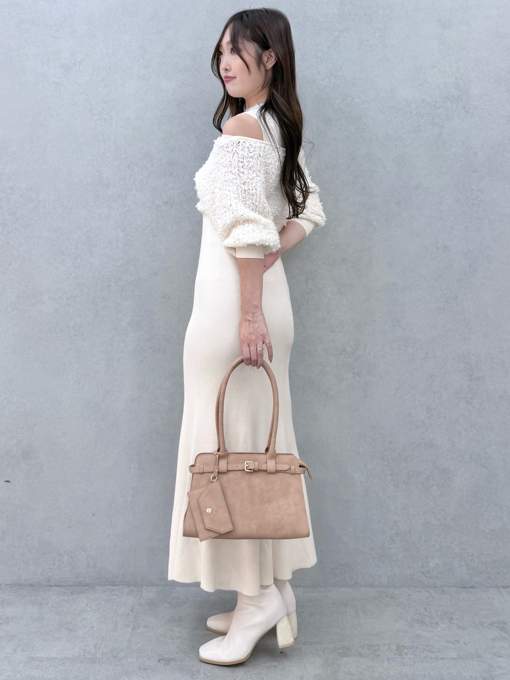 ホワイト系のワンピース、ホワイト系のブーツ、ベージュ系のハンドバッグを着用したレディースの秋コーディネートの3枚目の写真